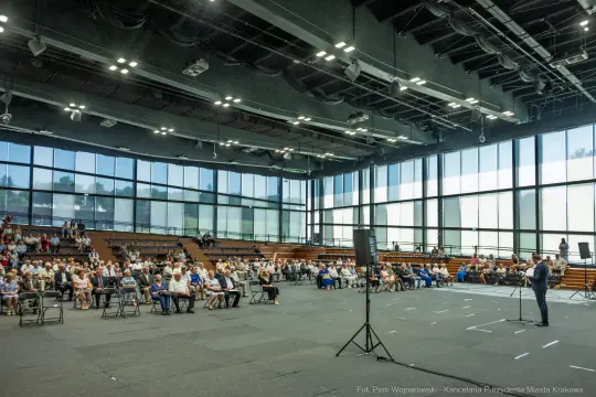 Wielka sala z publicznością siedzącą na widowni, mężczyzna przemawia na scenie.