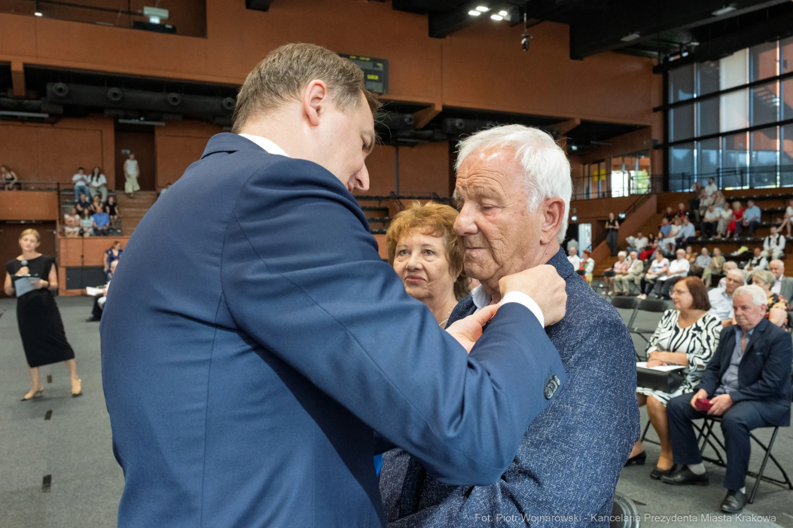 Uroczystość wręczenia odznaczeń, mężczyzna przypina medal starszemu mężczyźnie.  Autor: Piotr Wojnarowski