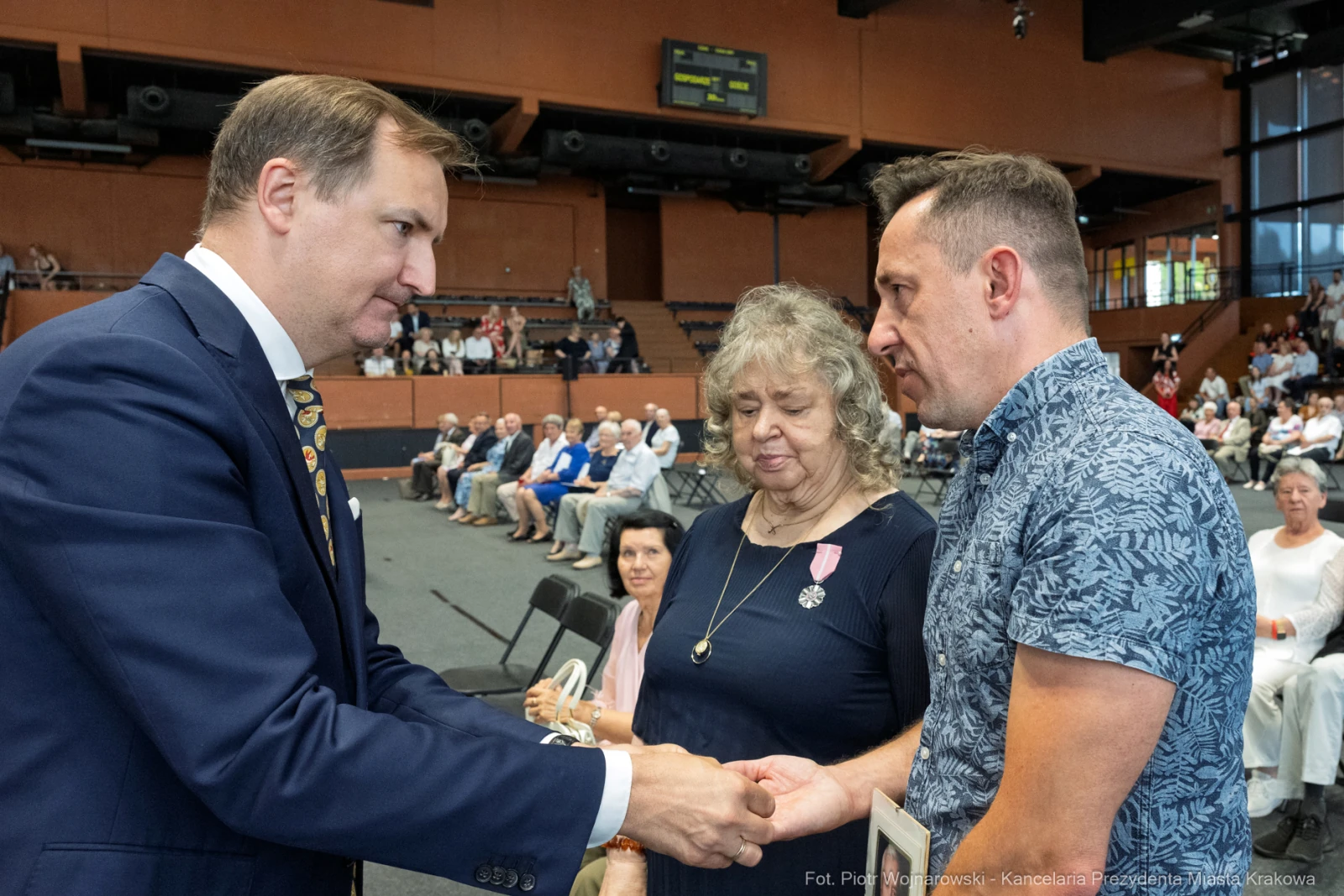 Wręczenie odznaczeń w trakcie uroczystości, uczestnicy w formalnych strojach.  Autor: Piotr Wojnarowski