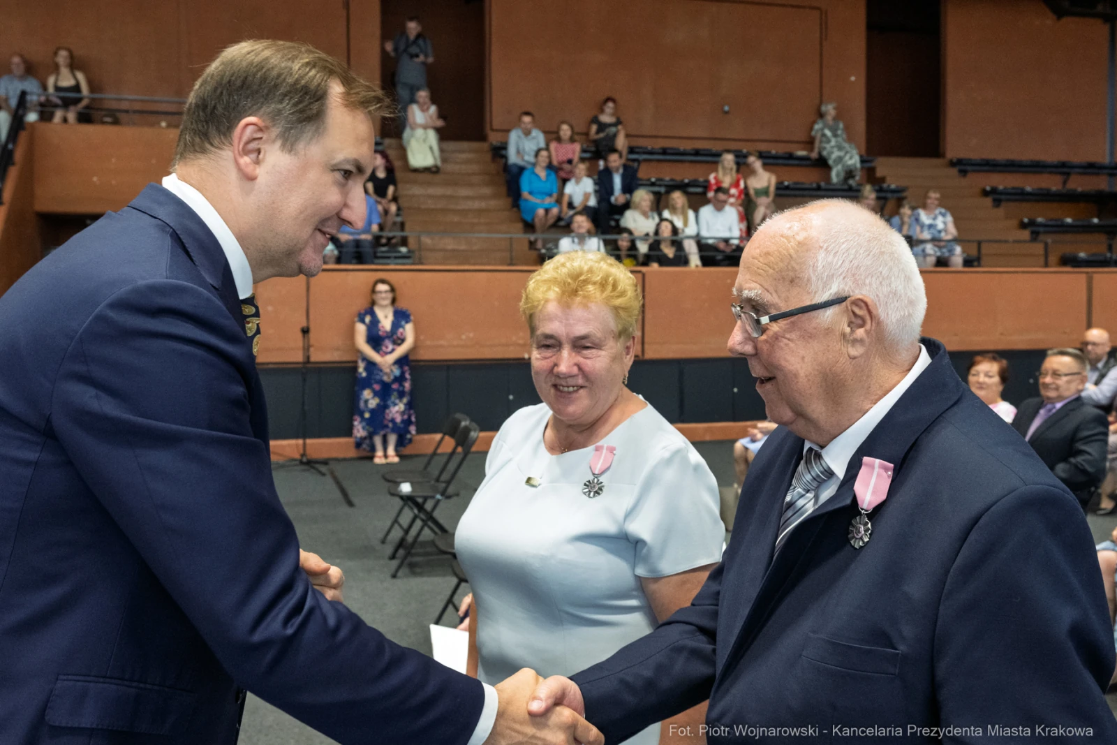 Uroczystość wręczenia odznaczeń, mężczyzna w garniturze wita starszego mężczyznę.  Autor: Piotr Wojnarowski