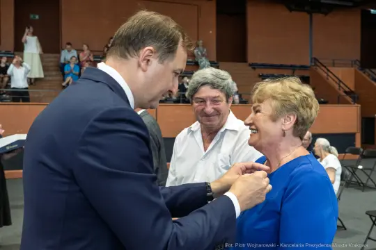 Uroczystość wręczenia odznaczeń, uśmiechnięte twarze, interakcja między ludźmi.