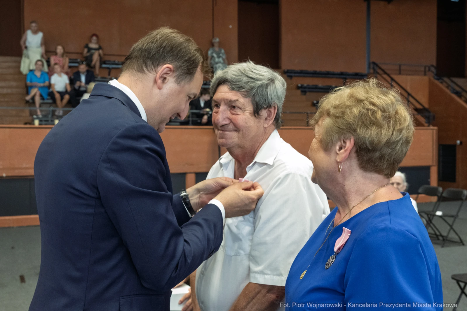 Wręczenie odznaczenia mężczyźnie przez urzędnika w obecności kobiety.  Autor: Piotr Wojnarowski