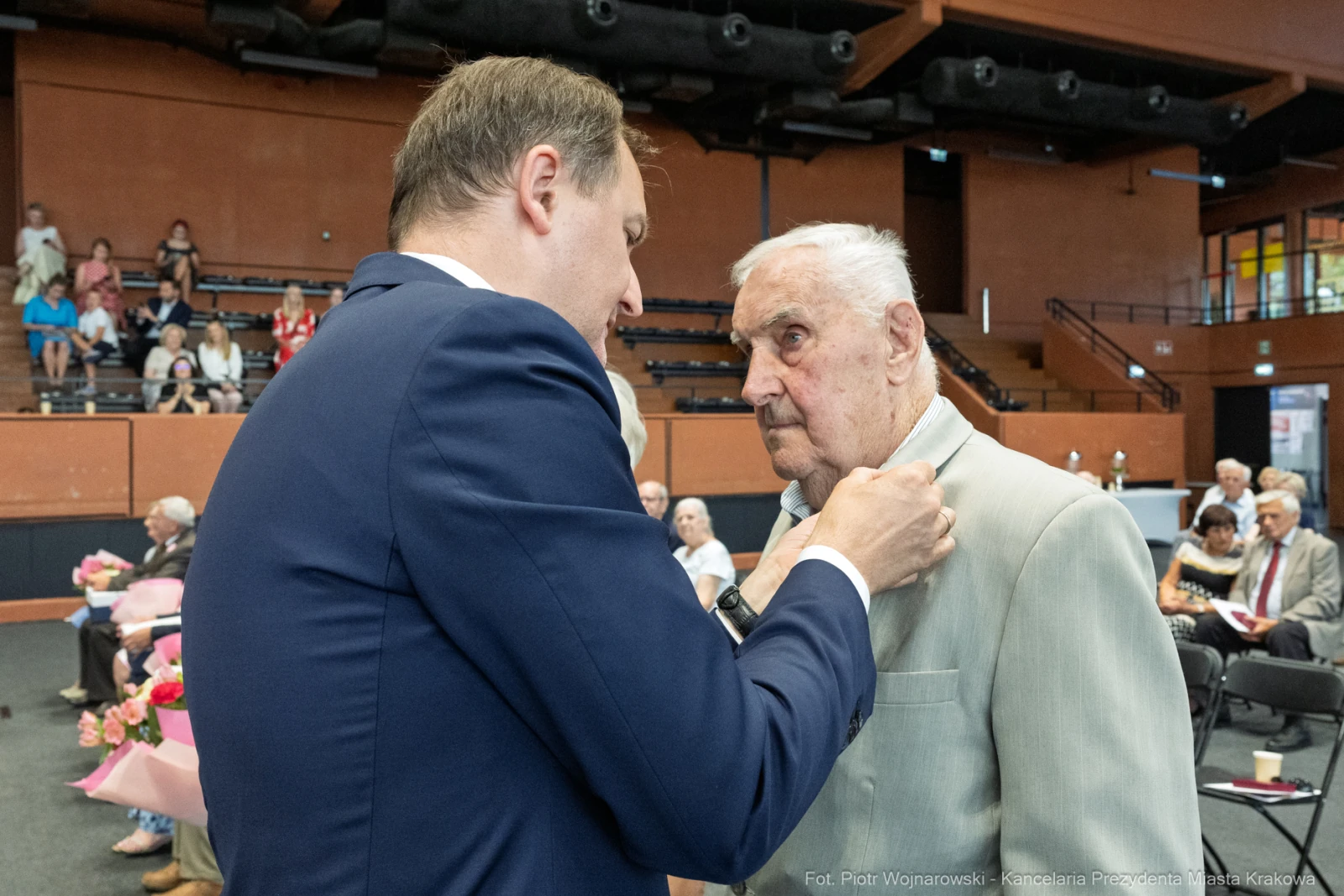 Mężczyzna przypina odznaczenie starszemu mężczyźnie podczas uroczystości.  Autor: Piotr Wojnarowski