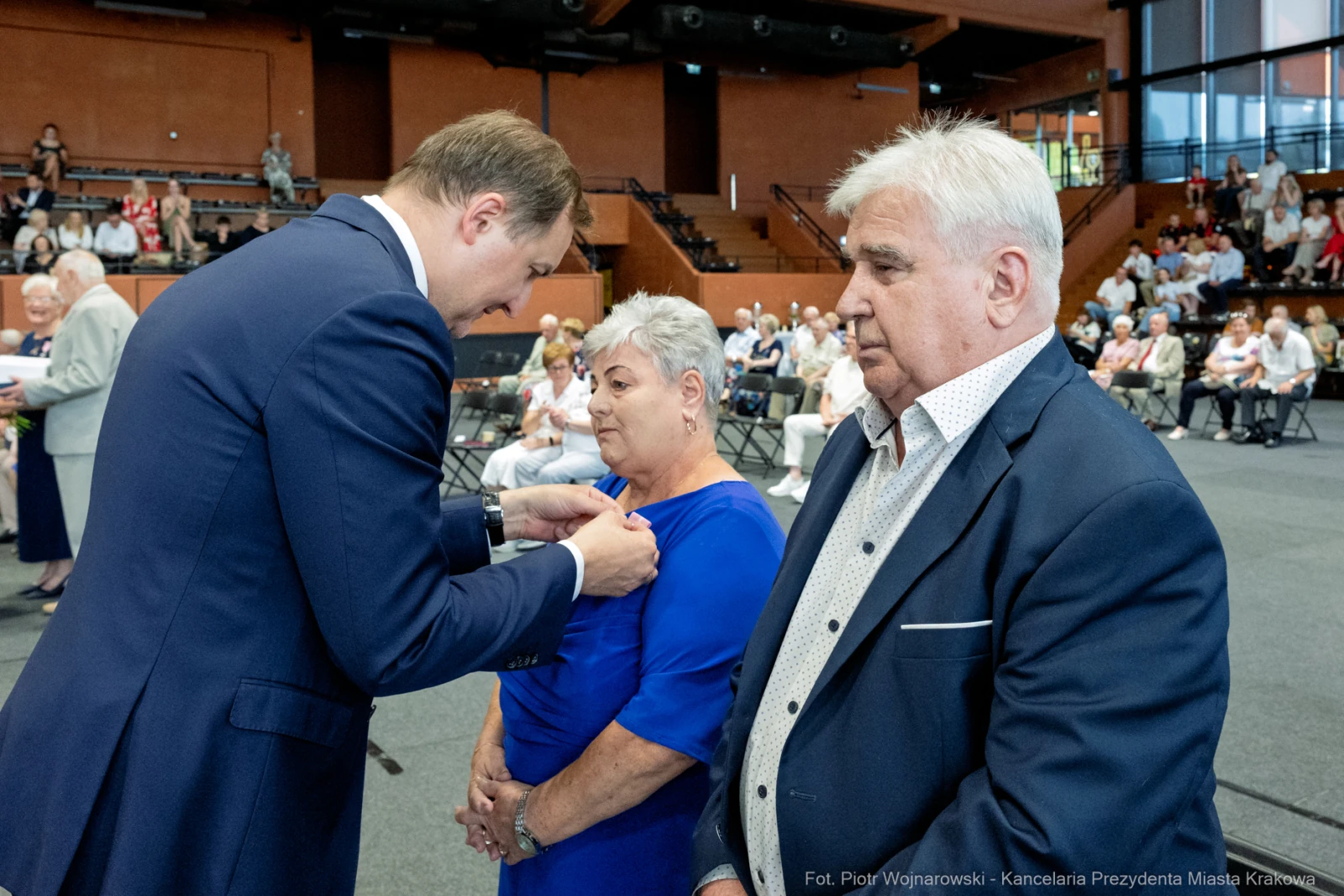 Wręczenie odznaczenia kobiecie przez mężczyznę w formalnym otoczeniu.  Autor: Piotr Wojnarowski