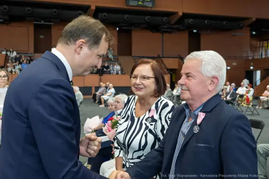 Uroczystość wręczenia nagród, uśmiechnięte twarze, gratulacje i kwiaty.