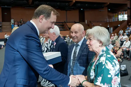 Uroczystość wręczenia nagród, uściski dłoni i uśmiechy uczestników.