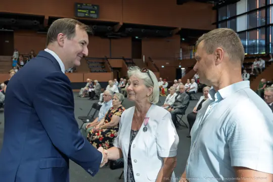Spotkanie z mieszkańcami, uściski dłoni i rozmowy w sali konferencyjnej.