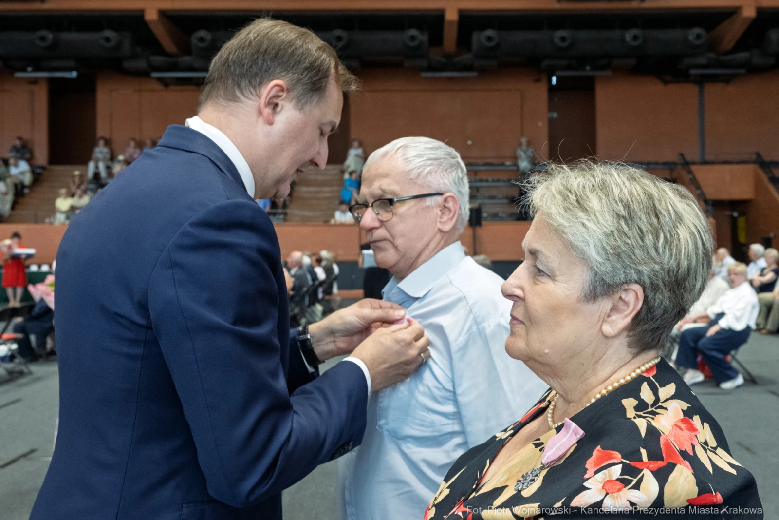 Wręczenie odznaczenia mężczyźnie przez urzędnika w obecności kobiety.  Autor: Piotr Wojnarowski