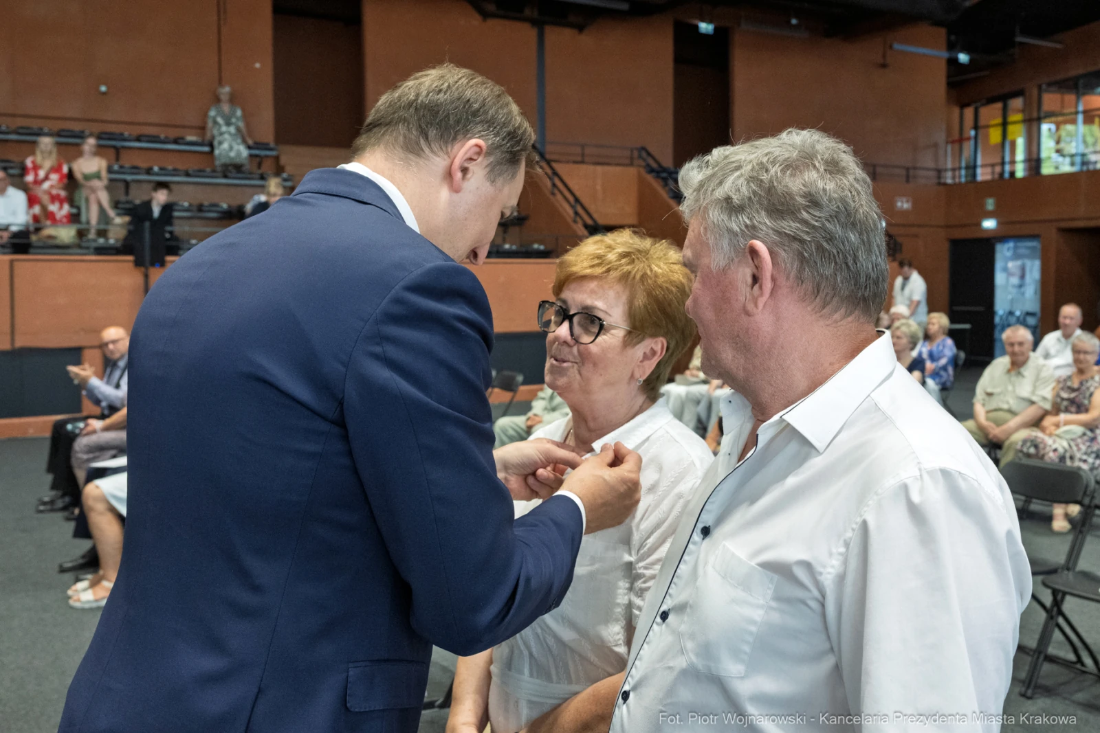 Wręczenie odznaczeń przez mężczyznę dwóm osobom w sali wypełnionej widownią.  Autor: Piotr Wojnarowski