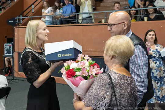 Wręczenie prezentu i bukietu kwiatów podczas uroczystości w Krakowie.