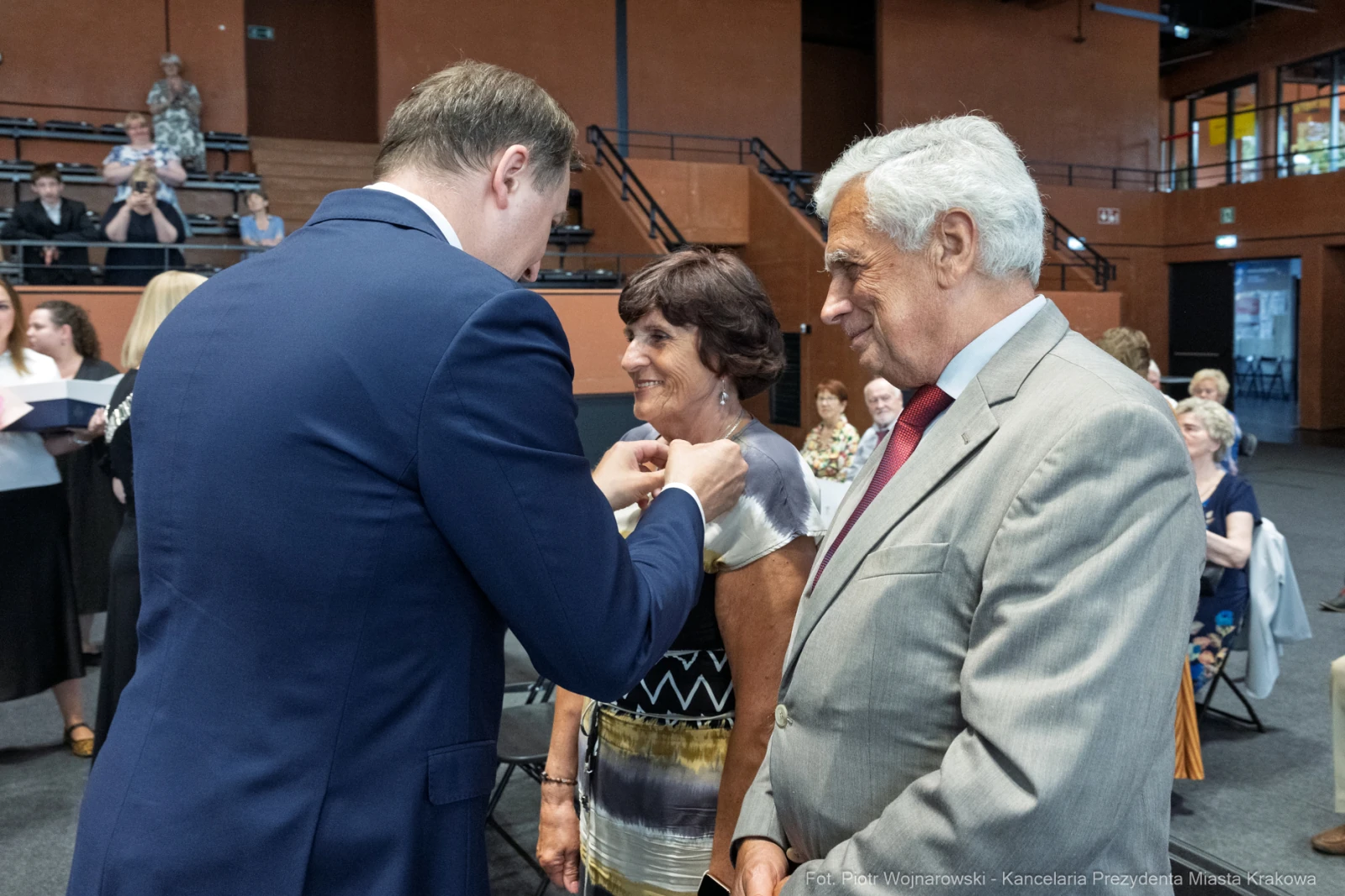 Uroczystość wręczenia odznaczeń, uśmiechnięte twarze, eleganckie stroje.  Autor: Piotr Wojnarowski