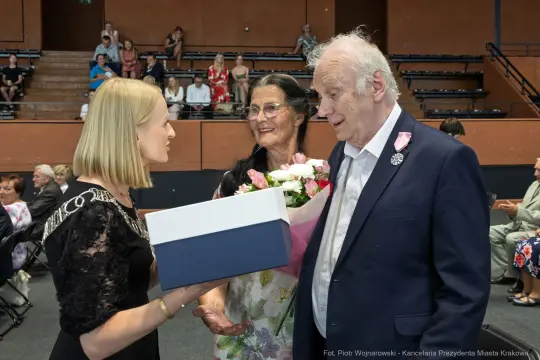 Wręczenie kwiatów i prezentu mężczyźnie przez kobietę w towarzystwie innej kobiety.