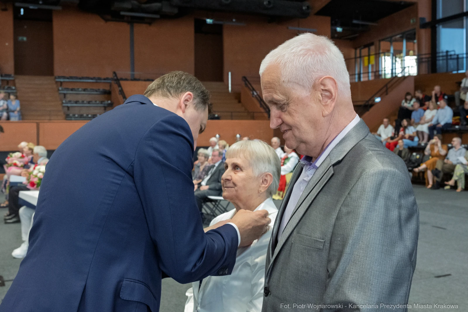Uroczystość wręczenia odznaczeń, osoby w formalnych strojach, sala wypełniona gośćmi.  Autor: Piotr Wojnarowski