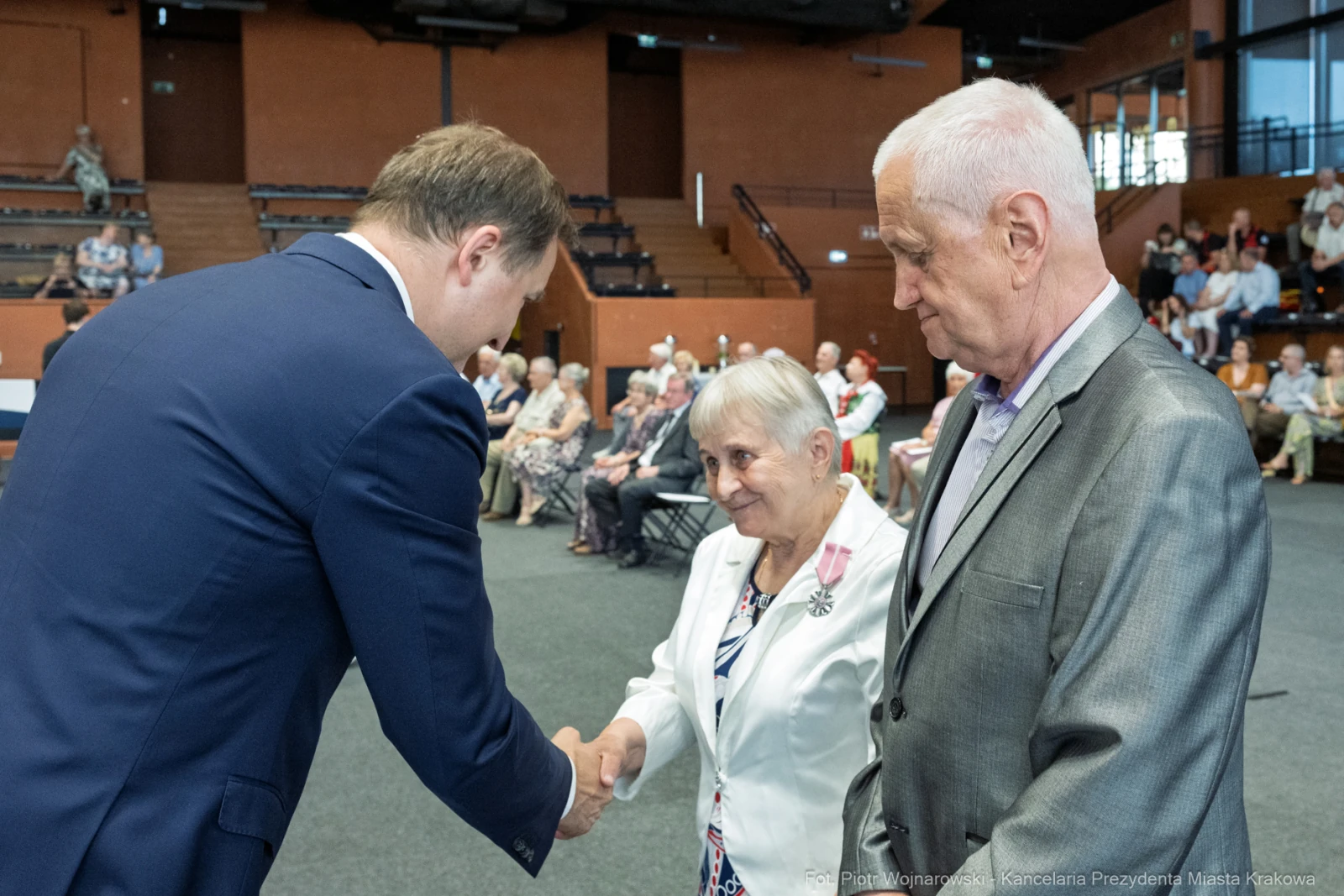 Uroczystość wręczenia odznaczeń, uściski dłoni, obecność gości w tle.  Autor: Piotr Wojnarowski
