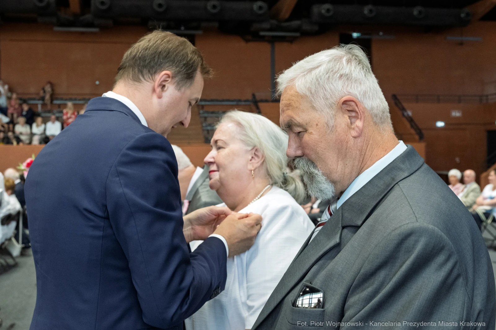 Wręczenie odznaczenia przez mężczyznę kobiecie w obecności starszego mężczyzny.  Autor: Piotr Wojnarowski
