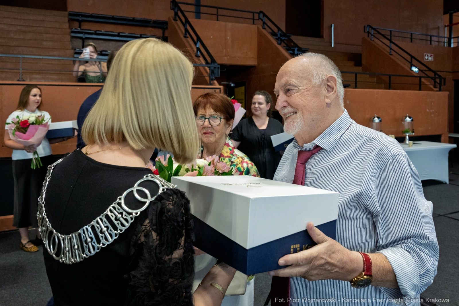 Wręczenie nagrody z okazji uroczystości, obecność gości z kwiatami.  Autor: Piotr Wojnarowski