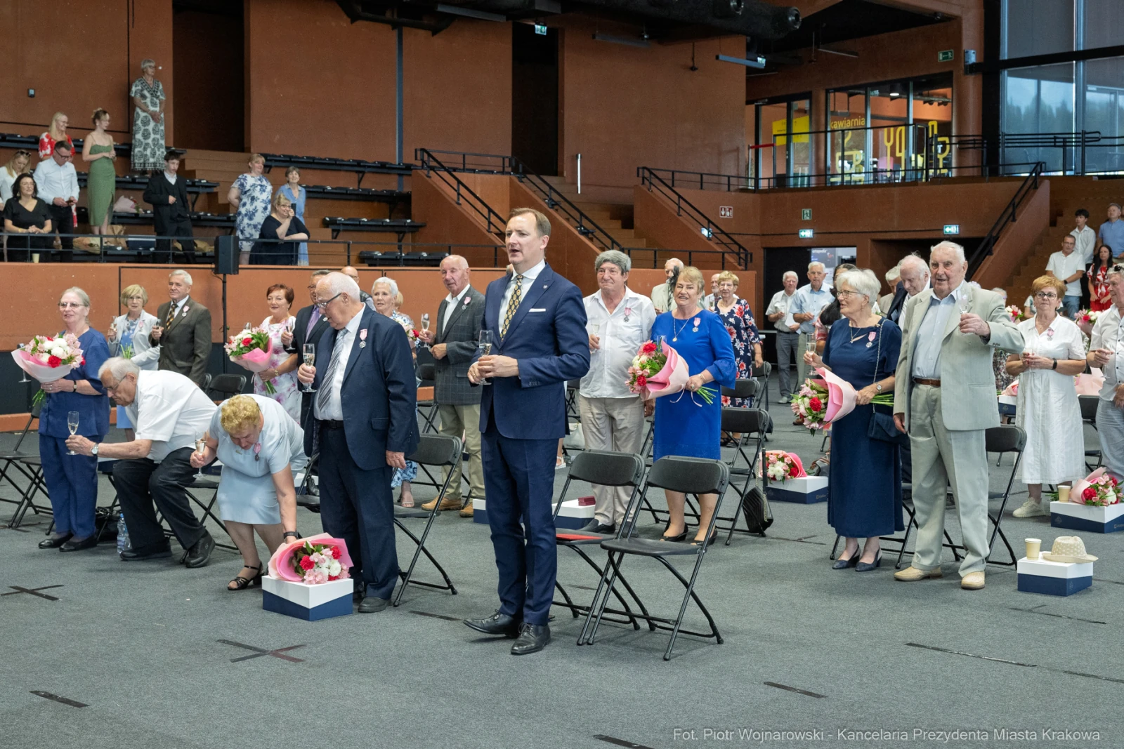Uroczystość z udziałem osób starszych, kwiaty, stojący mężczyzna w garniturze.  Autor: Piotr Wojnarowski