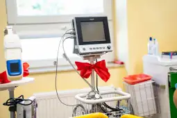 Monitor medyczny z czerwonymi wstążkami w szpitalnym otoczeniu.