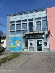 Budynek banku Credit Agricole z wejściem i reklamą usług.