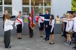 Uroczystość z przysięgą, młodzież w strojach galowych, trzymają sztandar.