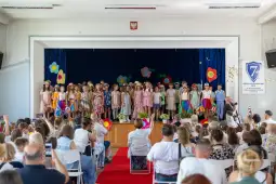 Dzieci w strojach występują na scenie podczas szkolnego przedstawienia.