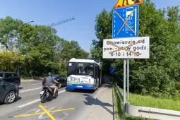 Autobus na przystanku, znak drogowy z informacją o godzinach obowiązywania zakazu.