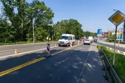 Ruch drogowy z oznaczeniami robót i pojazdami na jezdni.