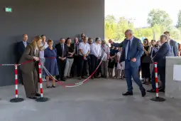 Uroczyste przecięcie wstęgi podczas otwarcia nowego obiektu. Obecni goście w tle.