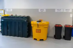 Zbiorniki na odpady w różnych kolorach i pojemności, oznaczone kodami segregacji.