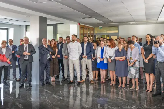 Grupa ludzi w eleganckich strojach podczas wydarzenia w nowoczesnym wnętrzu.