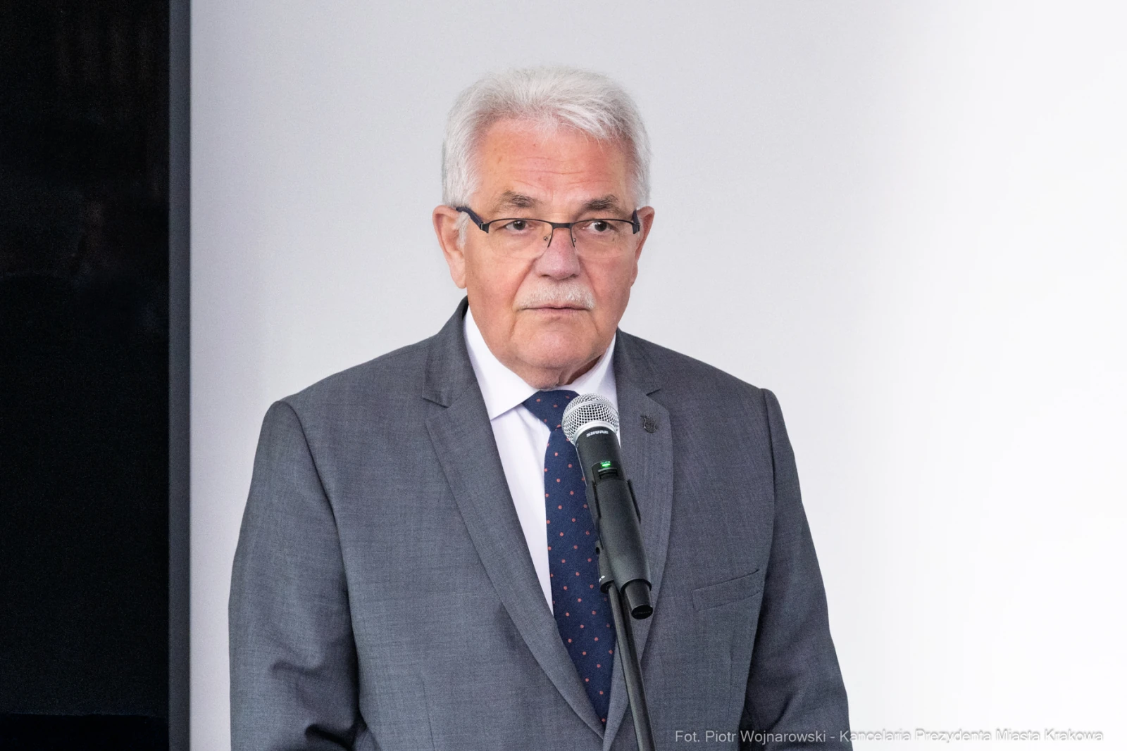 Mężczyzna w szarym garniturze przemawia do mikrofonu.  Autor: Piotr Wojnarowski