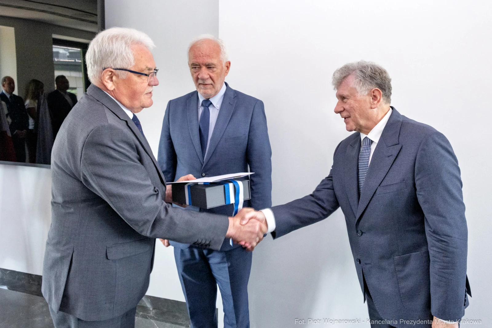 Trzech mężczyzn w garniturach, uścisk dłoni, formalne spotkanie.  Autor: Piotr Wojnarowski