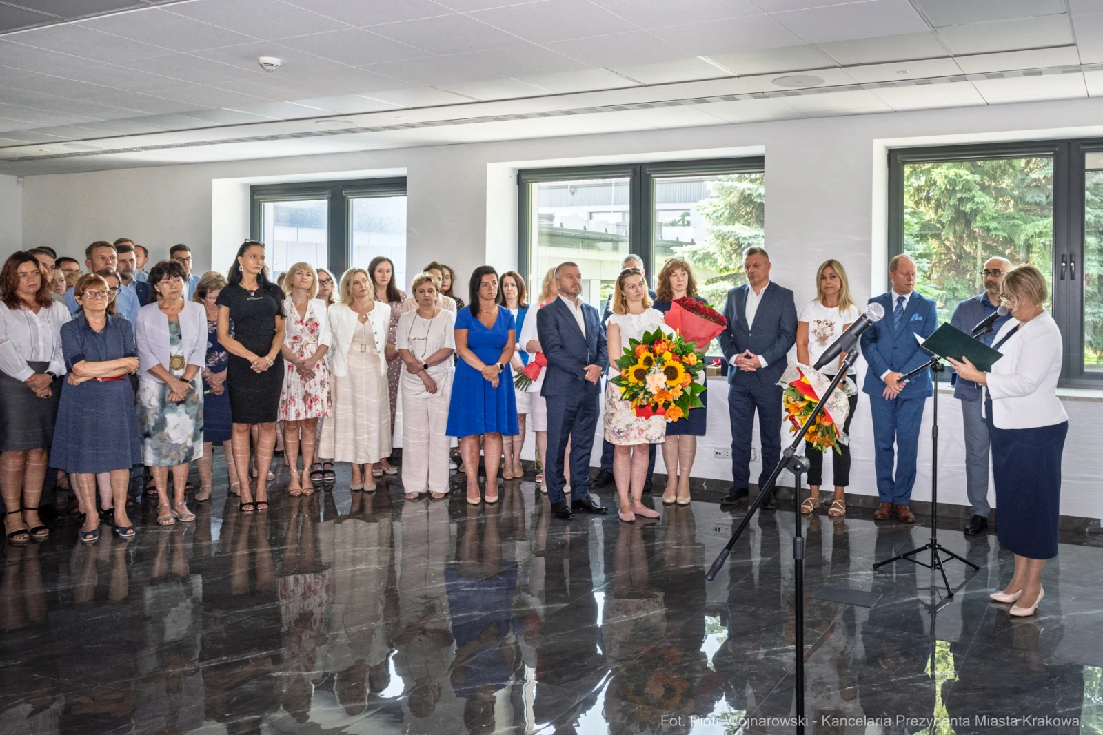 Uroczystość z kwiatami, przemówienia i zgromadzeni goście w eleganckim wnętrzu.  Autor: Piotr Wojnarowski