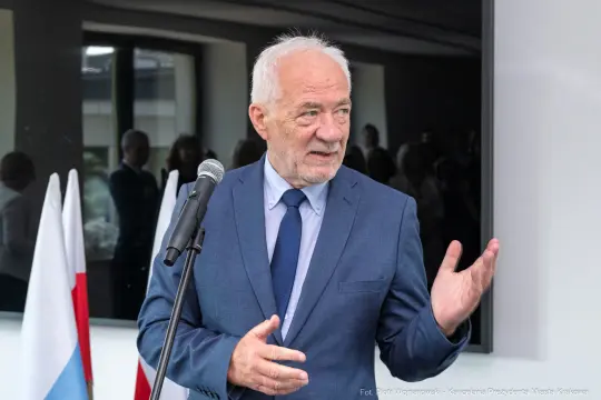 Mężczyzna w garniturze przemawia do zgromadzonej publiczności.
