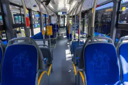 Wnętrze autobusu z niebieskimi siedzeniami i rysunkami postaci.