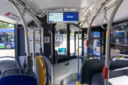 Wnętrze autobusu z widokiem na siedzenia i tablicę informacyjną.