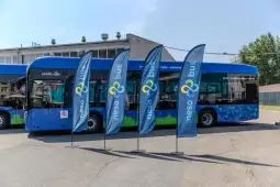 Nowoczesny autobus z logo neso bus oraz flagi reklamowe w tle.