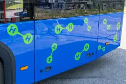 Niebieski autobus z zielonymi symbolami cząsteczek wodoru.