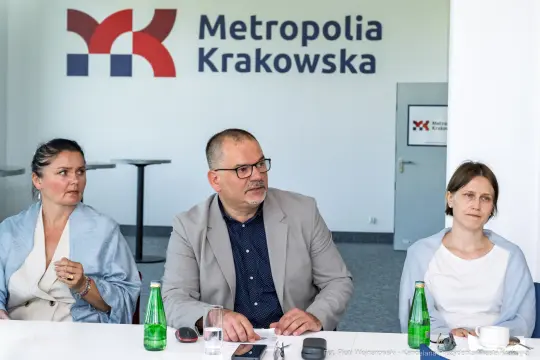 Spotkanie w biurze Metropolii Krakowskiej z trzema osobami przy stole.