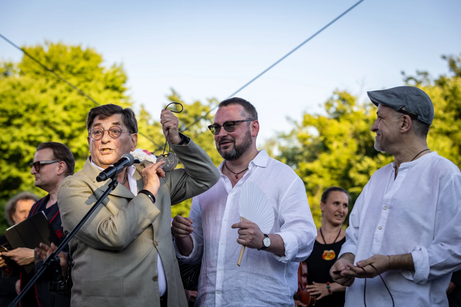 Mężczyźni na scenie podczas wydarzenia, jeden z nich trzyma mikrofon i medal.  Autor: Bogusław Świerzowski