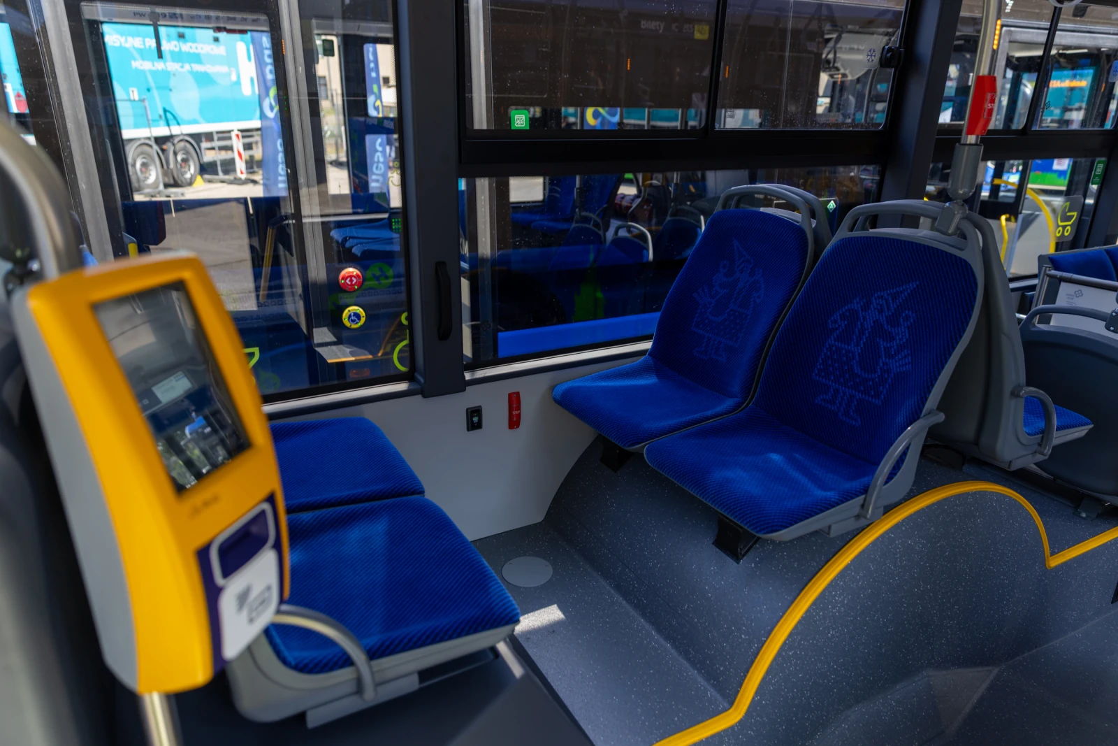 Wnętrze autobusu z niebieskimi siedzeniami i elektronicznym panelem informacyjnym.  Autor: Bogusław Świerzowski