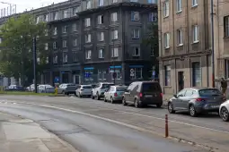 Ruch samochodowy na ulicy z budynkami w tle.