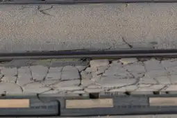 Krawędź torów kolejowych z widocznymi pęknięciami w nawierzchni.