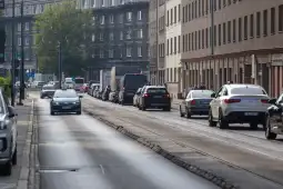 Ruch uliczny w mieście, samochody zaparkowane i poruszające się wzdłuż jezdni.