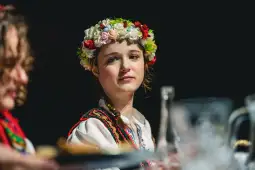 Dziewczyna w tradycyjnym stroju ludowym z kwiatowym wiankiem na głowie.