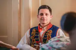Mężczyzna w tradycyjnym stroju ludowym z uśmiechem.