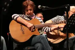 Kobieta grająca na gitarze akustycznej podczas występu muzycznego.