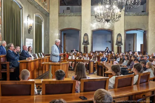 Spotkanie w sali obrad z prelegentem i publicznością, w tle siedzący goście.