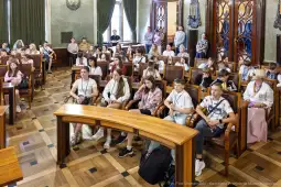 Grupa młodzieży siedząca w sali obrad, uczestnicząca w spotkaniu.