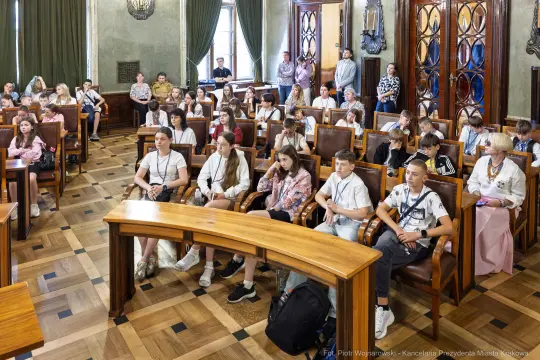 Grupa młodzieży siedząca w sali obrad, uczestnicząca w spotkaniu.